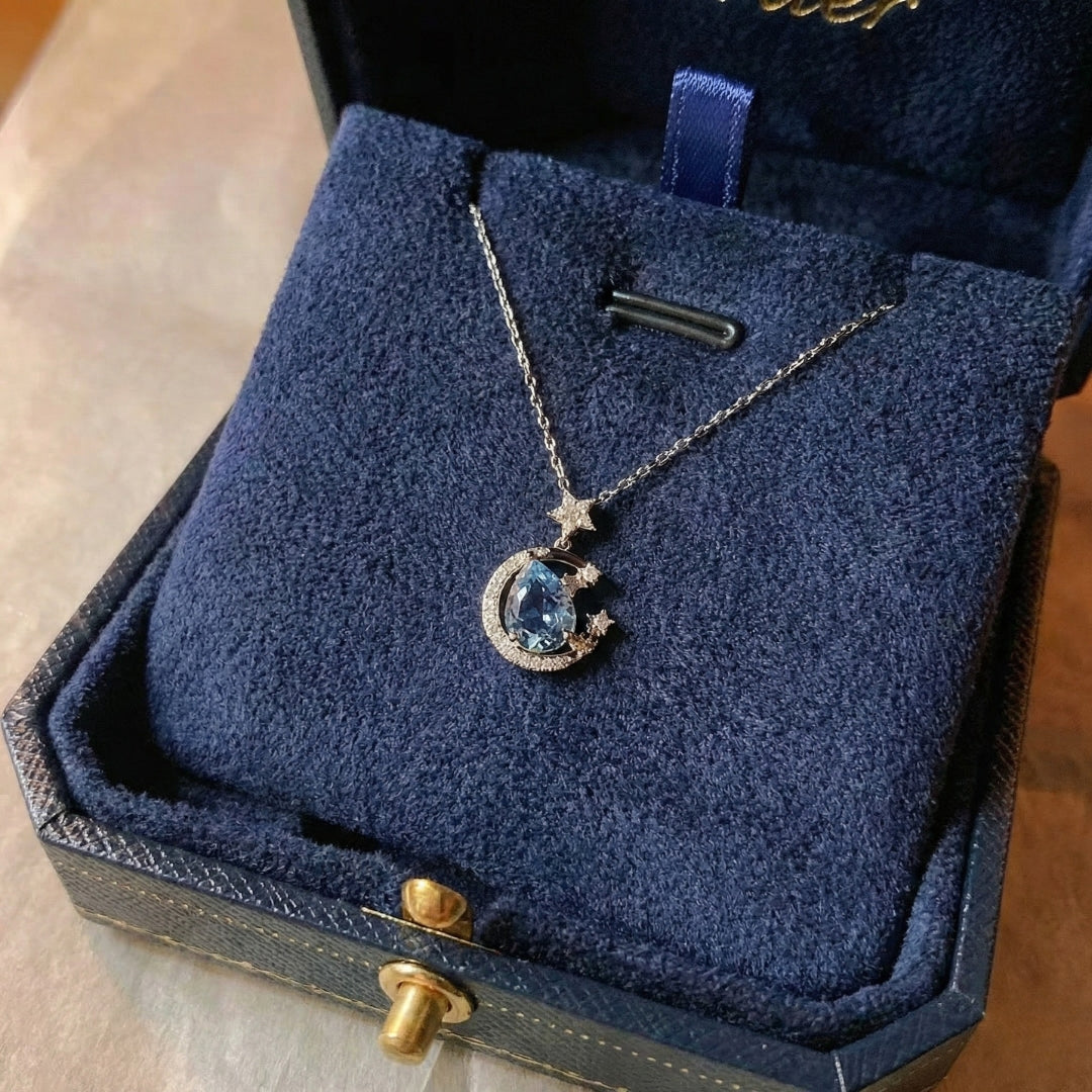 The Moondust Whisper Necklace captures the ethereal beauty of a moonlit sky, featuring a mesmerizing blue water-drop stone nestled within a delicate celestial crescent. It brings a sophisticated sense of wonder to any look.
