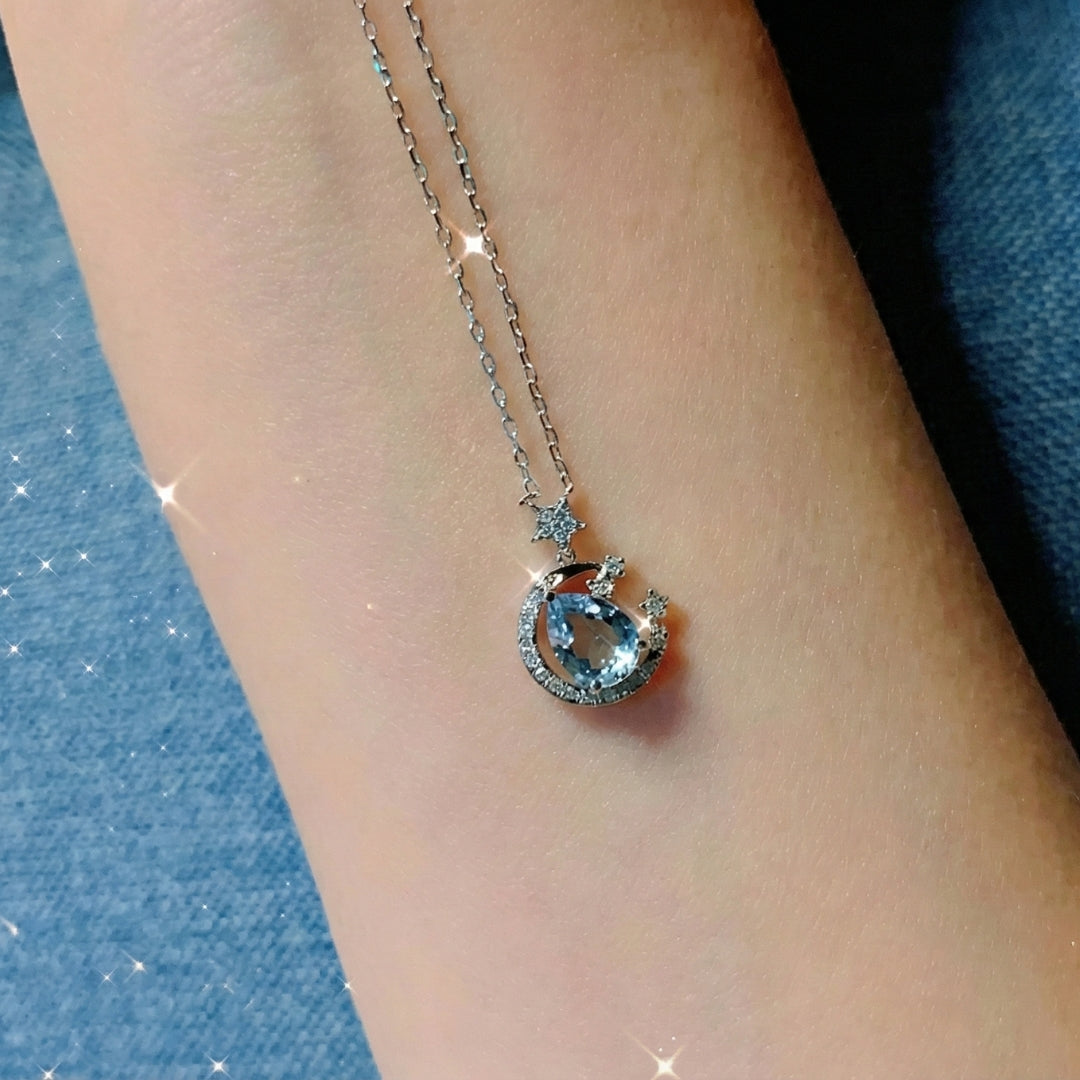 The Moondust Whisper Necklace captures the ethereal beauty of a moonlit sky, featuring a mesmerizing blue water-drop stone nestled within a delicate celestial crescent. It brings a sophisticated sense of wonder to any look.