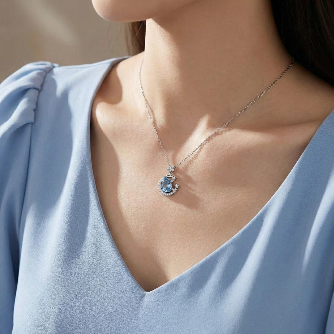 The Moondust Whisper Necklace captures the ethereal beauty of a moonlit sky, featuring a mesmerizing blue water-drop stone nestled within a delicate celestial crescent. It brings a sophisticated sense of wonder to any look.