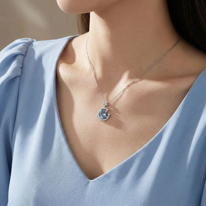 The Moondust Whisper Necklace captures the ethereal beauty of a moonlit sky, featuring a mesmerizing blue water-drop stone nestled within a delicate celestial crescent. It brings a sophisticated sense of wonder to any look.